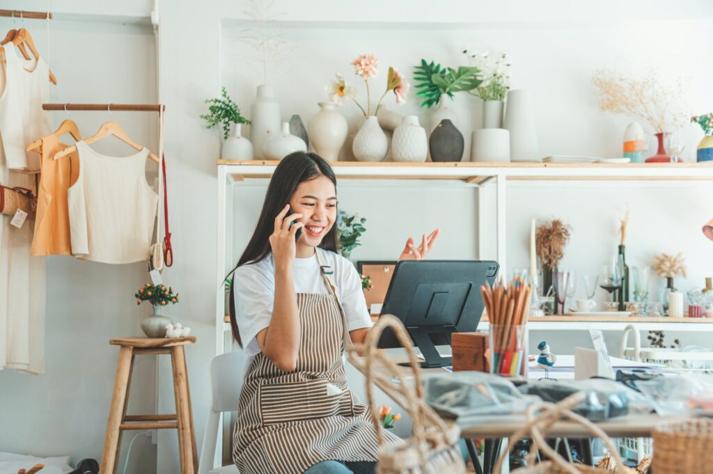 Small business owner talking on the phone with customers in a small shop.